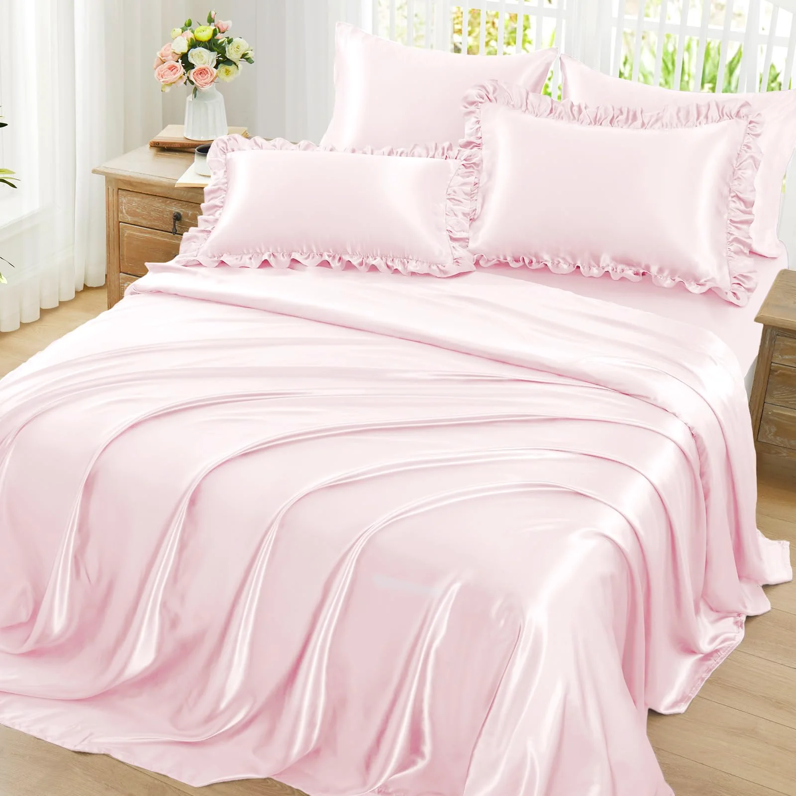 A queen bed dressed in blush pink ruffled satin, pillowcases ruffled to match